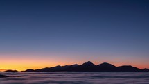 Beautiful Blue sky above mountains silhouette in foggy nature landscape after sunset Time lapse
