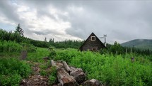 Time lapse of clouds flying over cottage in mountain forest 
