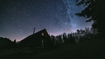 Time lapse Fairytale night sky with millions stars of milky way galaxy above wooden hut in wild forest nature Astronomy
