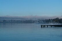 Misty lake view with pier and town in background