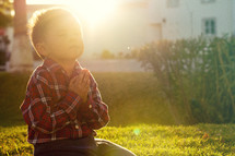 a boy praying under the glow of sunlight 