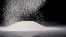 Pouring white flour on black table in slow motion 