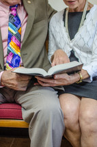 an elderly couple reading a Bible together 