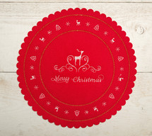 Red fabric cloth or tablemat with Merry Christmas text. Christmas centerpiece on white wooden background.
