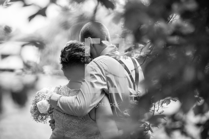 a groom hugging his mother before a wedding 