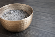 Bowl of ashes on a dark wood background with copy space 