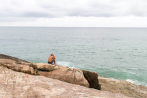 a man sitting on a shore contemplating 