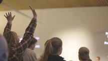 Young adult worshiping with hands raised in the air.