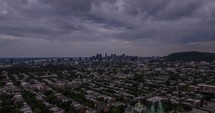 Overcast cityscape with a distant view of downtown skyscrapers, set against a moody sky, from a drone