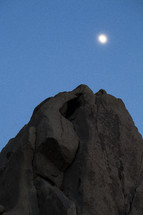 moon above a rock formation 