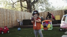 little boy playing football in the backyard 