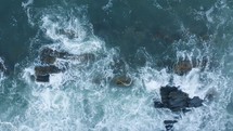 Aerial shot of waves crashing against rocks