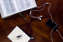 open Bible, earbuds, podcast, table, Bible, cellphone, ipod, mp3 player, pen, journal, scripture 