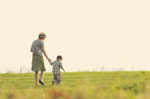 Mother and son walking in a grassy field