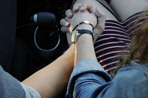 a couple holding hands in a car 