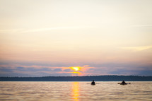 Rowers in the water at sunset.