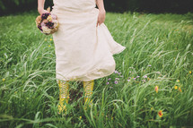 bride walking in a field in rain boots