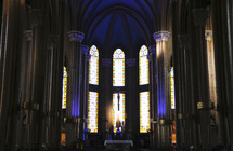 Interior of cathedral with light shining through stained glass windows.