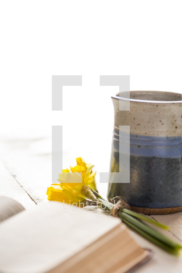 a cup of coffee with a Bible and flowers