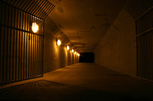 gated tunnel lined with lights leading out of darkness
