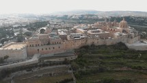 View of Mdina city outside city walls, revealing the Cathedral of Saint Paul  - Aerial Pan forward shot