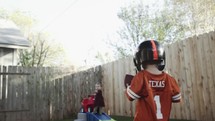 a little boy playing football in the backyard 