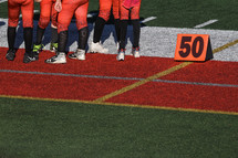 Football players standing at the 50 yard line