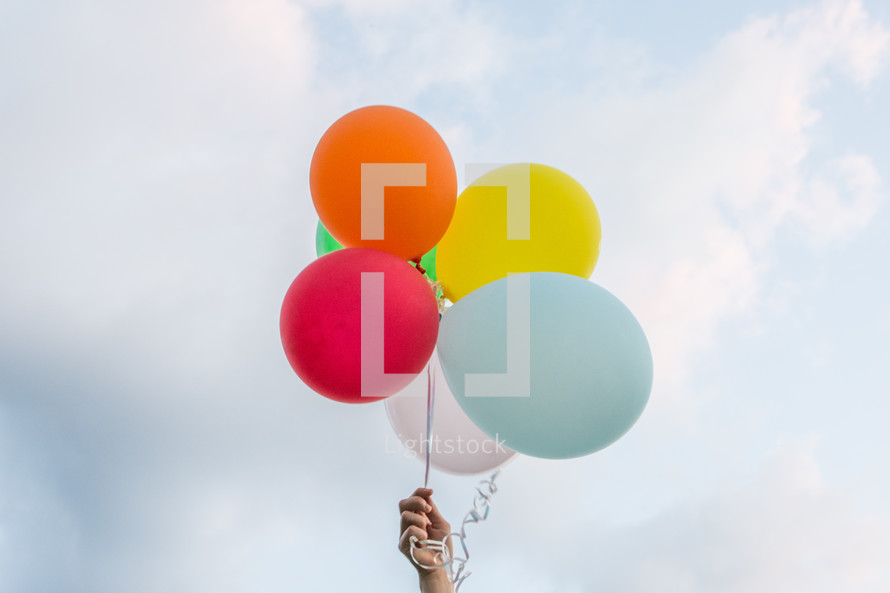 a bunch of colorful balloons with cloudy skies