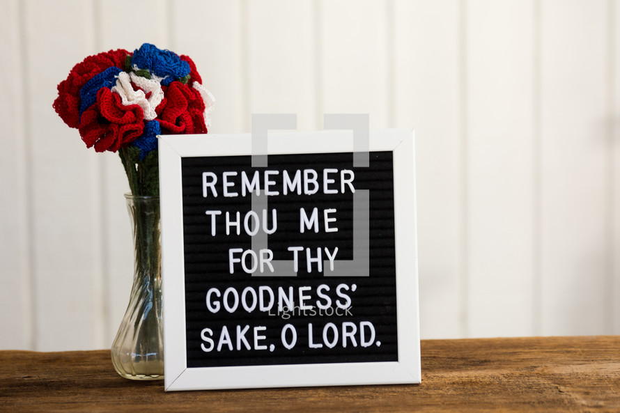 a bible verse on a sign board with crocheted flowers