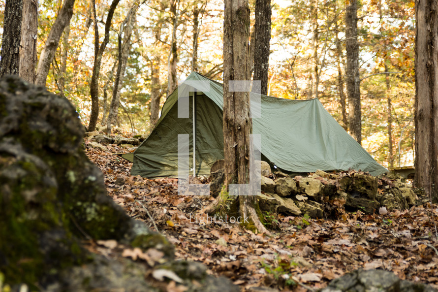 a green military tent in the woods