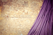 Purple drape against plywood.
