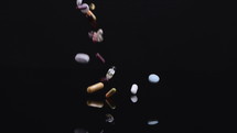 Different pills falling on black background. 