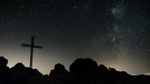 Stars with milky way galaxy moving over cross in top of the mountains Time lapse
