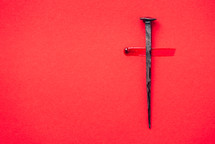 Cross made from nail and blood on a red background - Good Friday