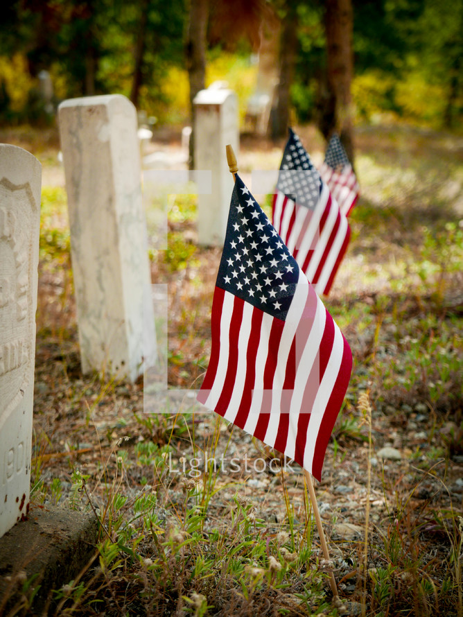 American flags beside very old grave markers 