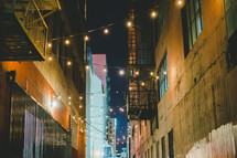 string of lights hanging over an alley at night 