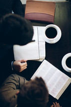 two men reading from a Bible during a Bible study