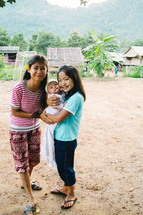 little girls holding a newborn baby in a village 