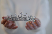 a woman holding out a tiara 