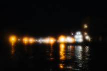 blurry city lights across a river at night 