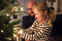 father and daughter decorating a Christmas tree 