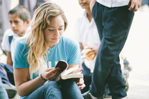 A woman sitting and reading a Bible.