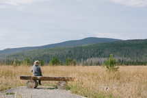 child sitting alone on a log bench 