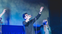 worship leaders performing on stage in front of a projection screen 