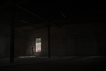 woman standing at a window in an empty warehouse 