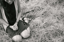 young woman kneeling praying in grass 