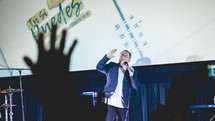 worship leaders performing on stage in front of a projection screen 