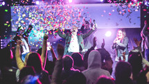 confetti falling and woman holding a microphone and singing during a worship service 