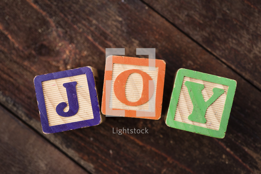 The word "joy" spelled out with children's wooden blocks.