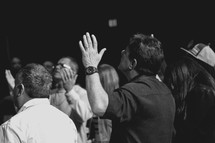 men with raised hands during a worship service 
